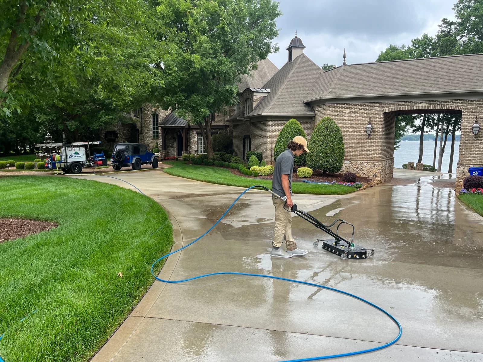 Ridge Curwood pressure washing a concrete driveway with a surface cleaner in a Huntersville NC neighborhood