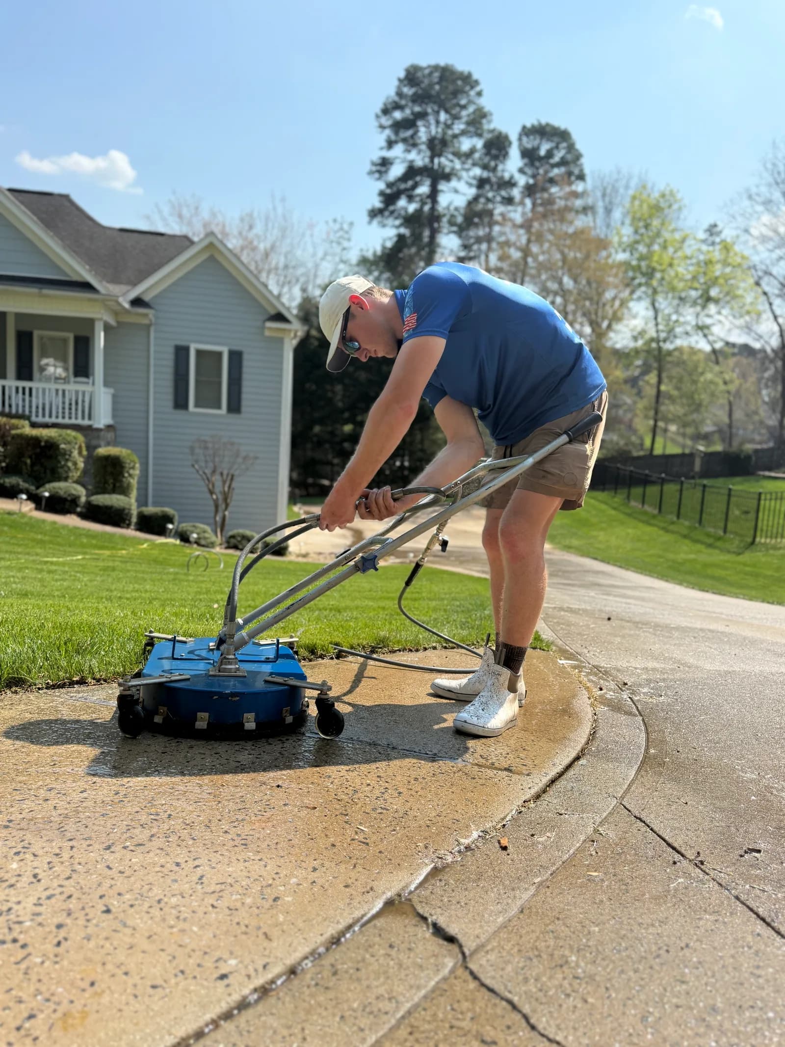 Ridge Curwood pressure washing a concrete driveway with a surface cleaner in a Denver NC neighborhood