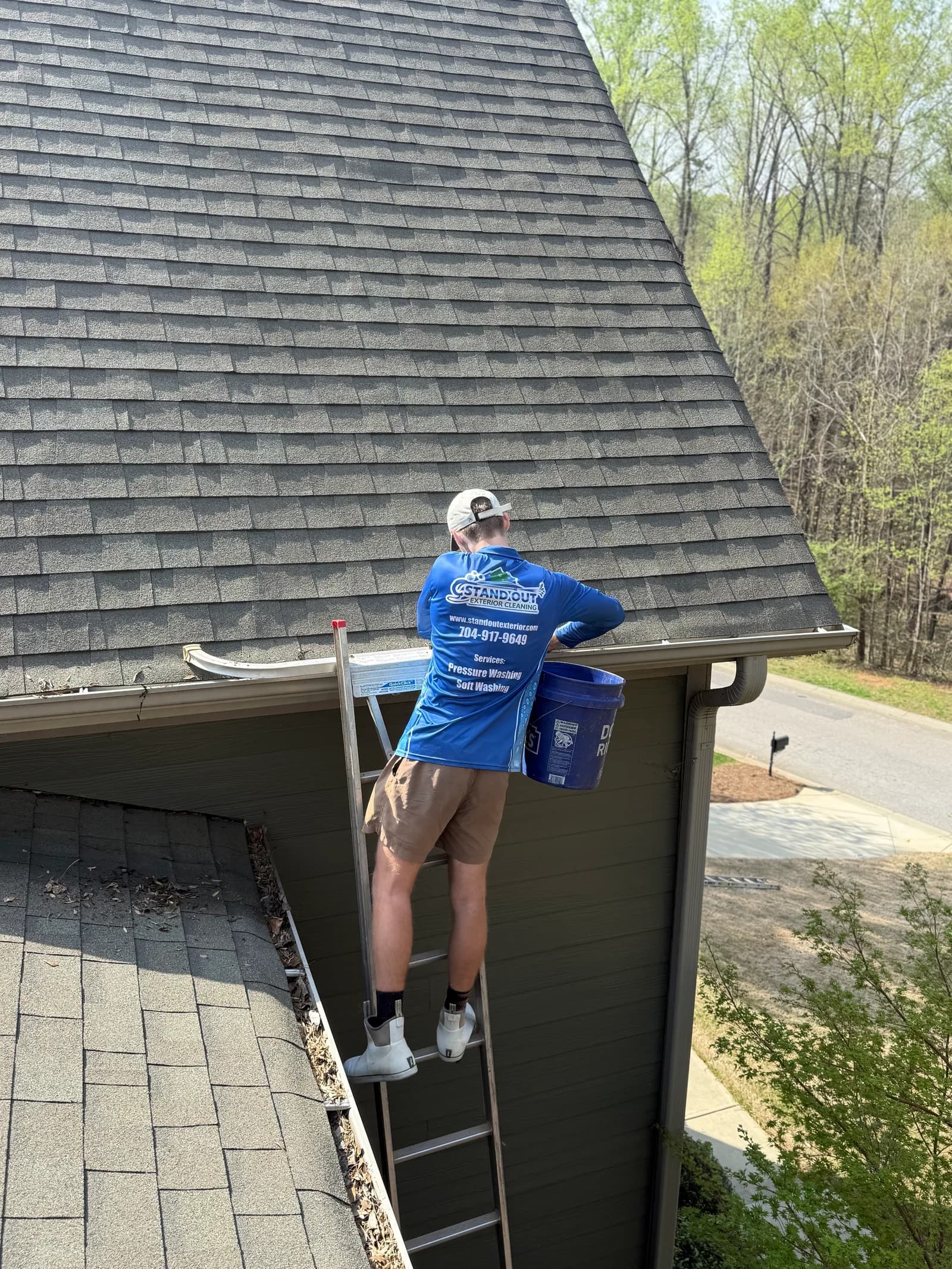 Ridge Curwood on a ladder cleaning gutters at a two-story home in Huntersville NC