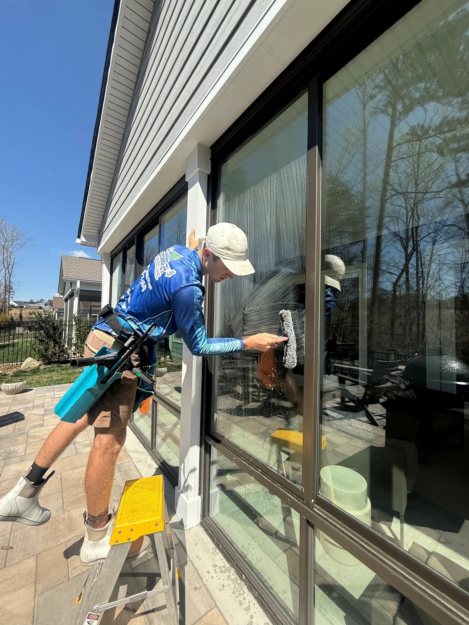 Ridge Curwood reaching a second-story window with a pure-water pole on a Huntersville NC home