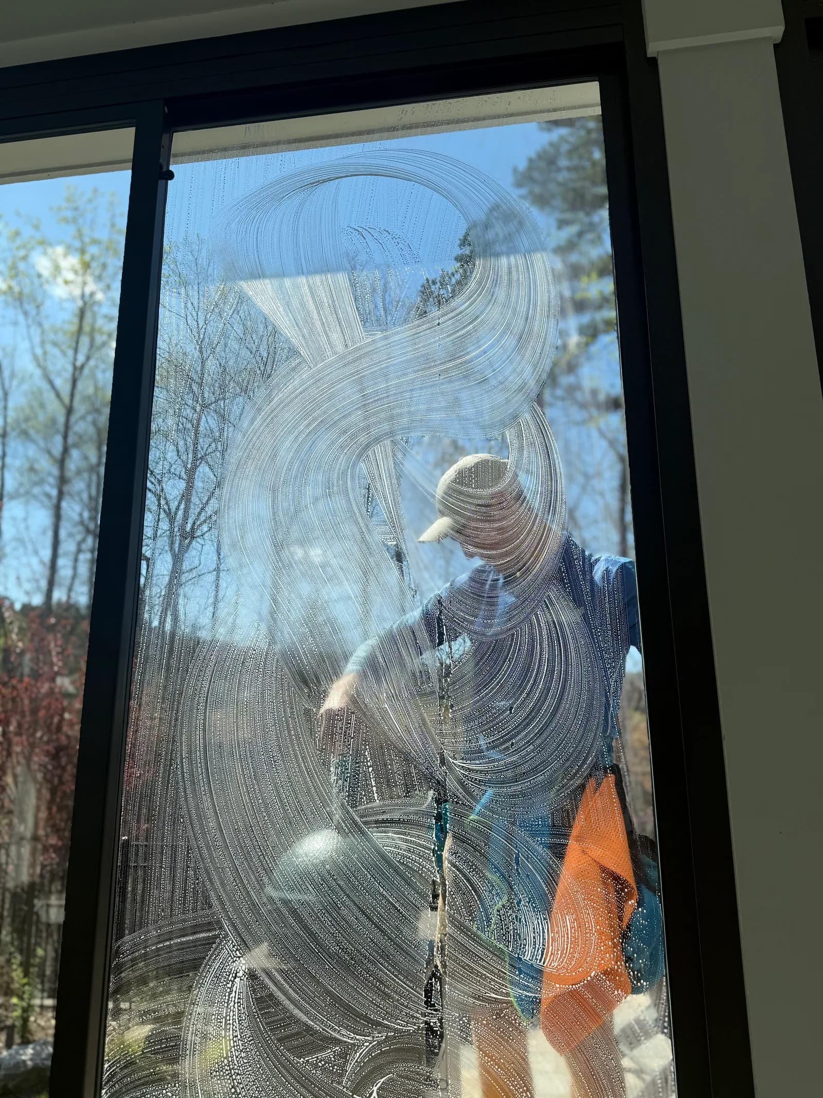 Ridge Curwood cleaning a large window with a squeegee in Denver NC